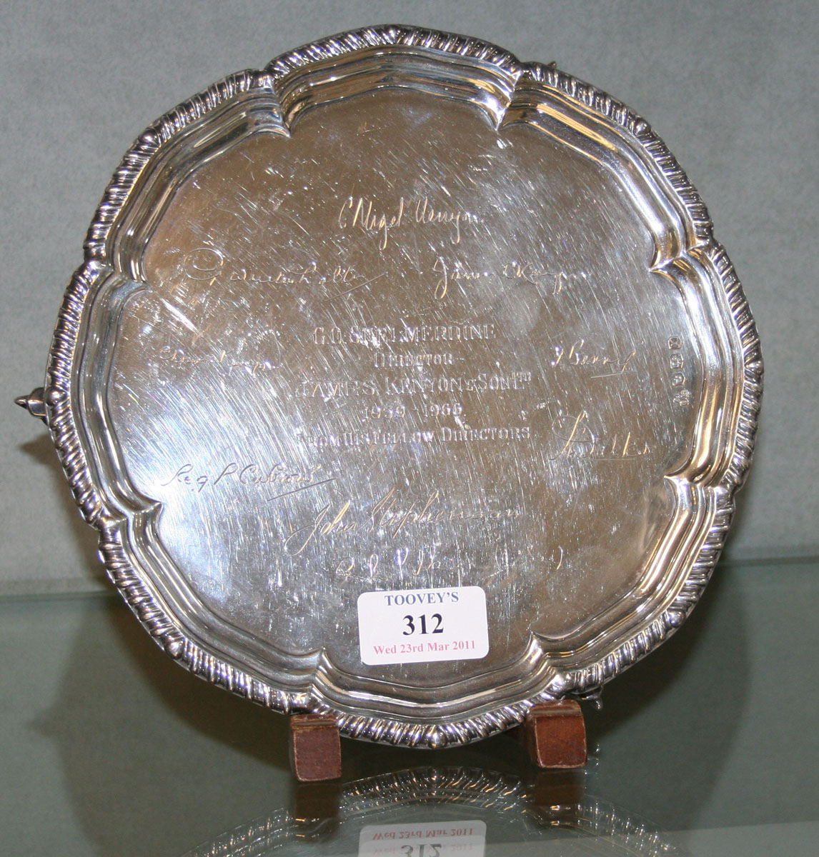 A silver salver with gadrooned rim on three volute scroll feet ...