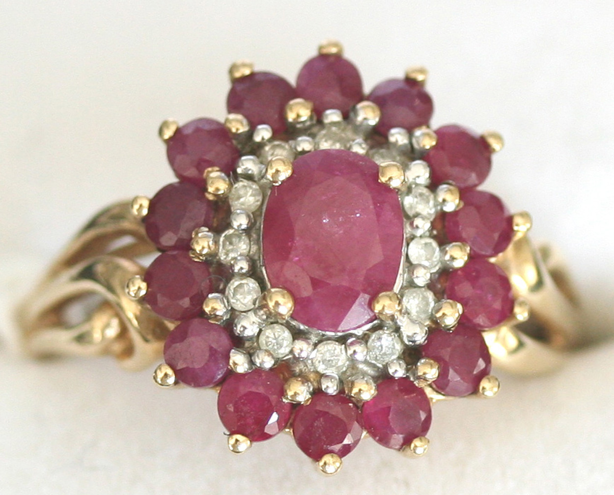 A 9ct gold, ruby and diamond set oval cluster ring, mounted with the ...