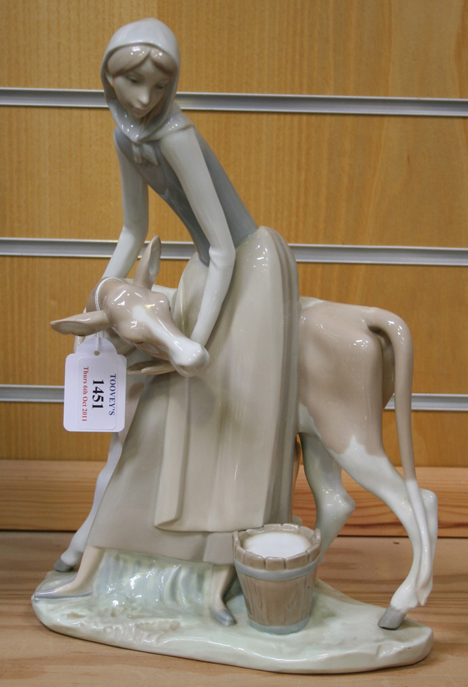 A Lladro porcelain model of a milkmaid and cow, raised on a