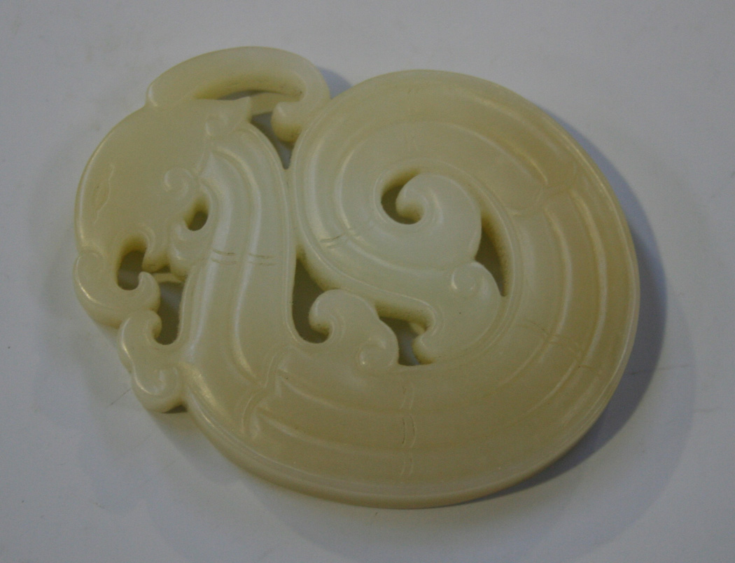 a-chinese-jade-carving-in-the-form-of-a-coiled-stylized-phoenix-the