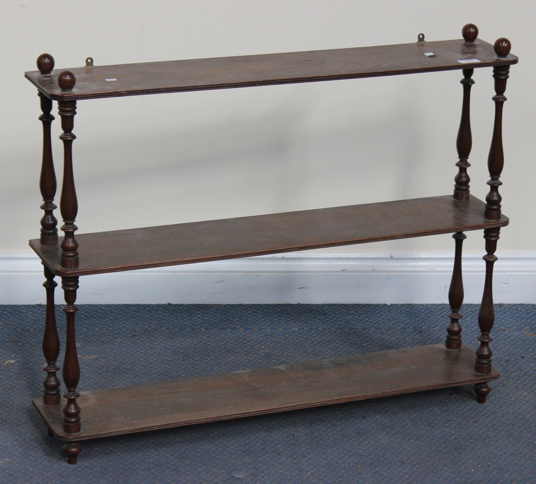 A Victorian style mahogany three-tier hanging wall shelf with turned ...