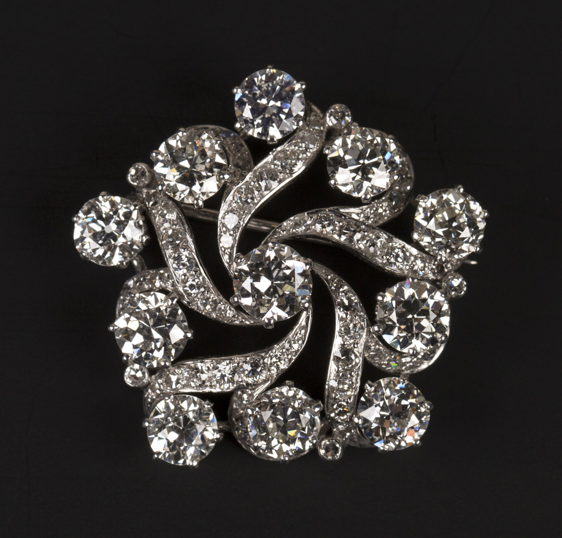 A diamond brooch in a swirling pentagonal shaped openwork design, claw ...