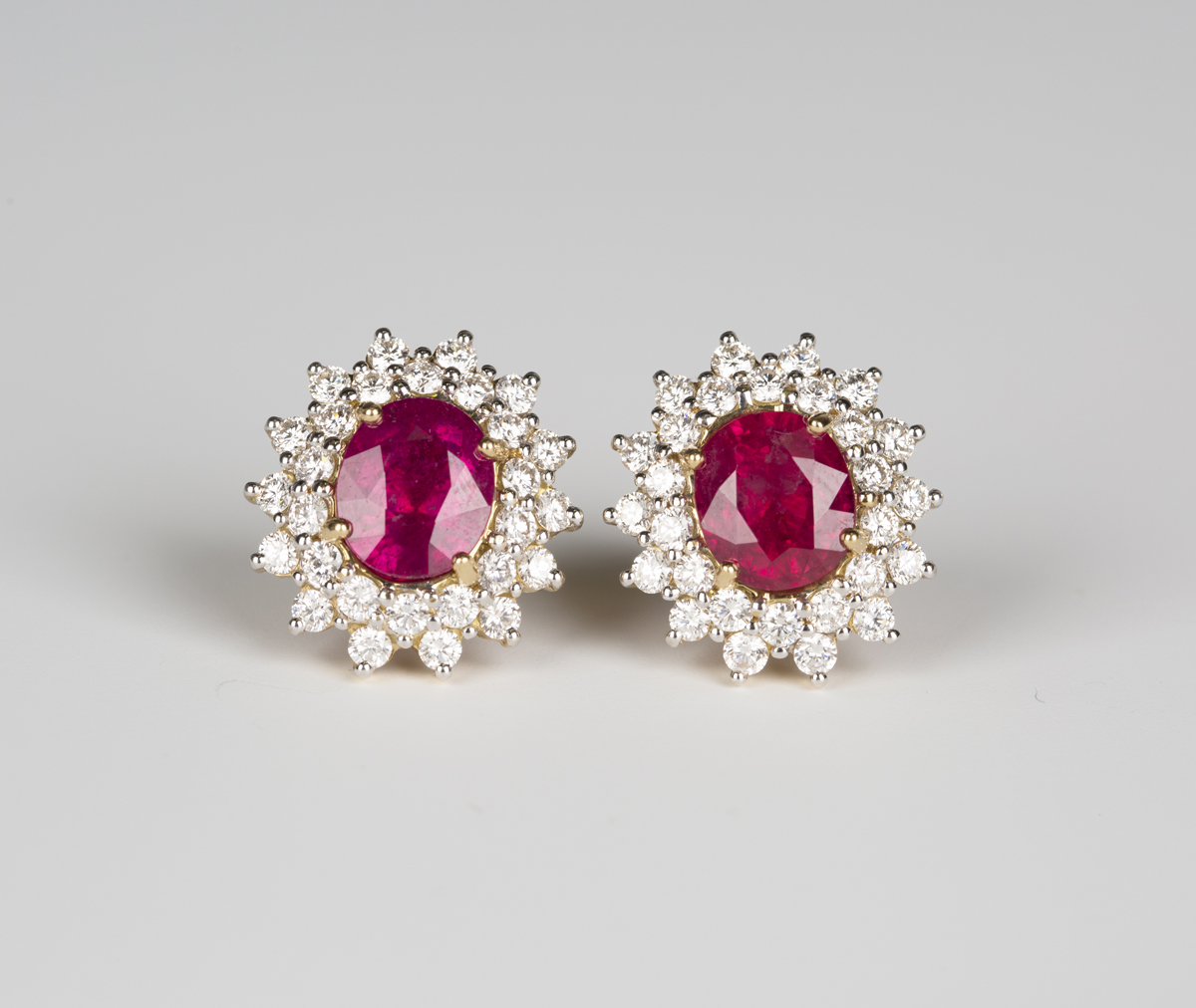 A pair of 18ct gold, ruby and diamond oval cluster earrings, each claw ...