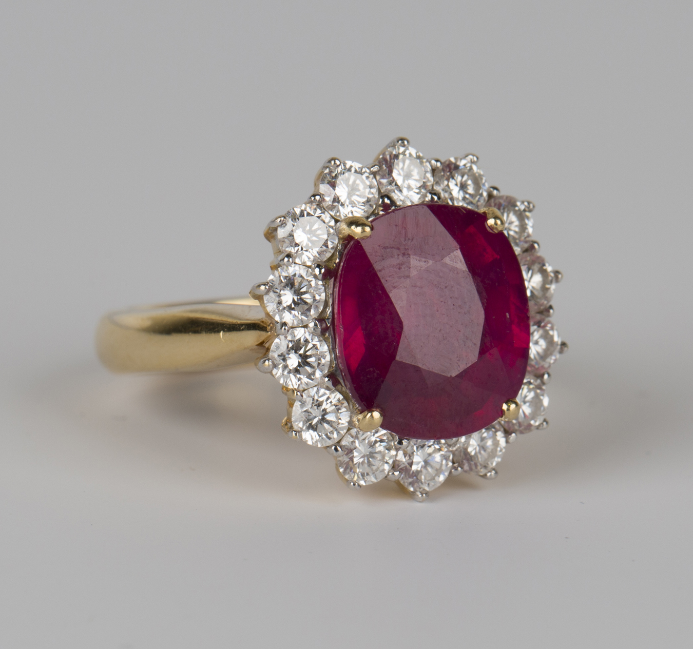A gold, diamond and treated ruby oval cluster ring, claw set with the ...