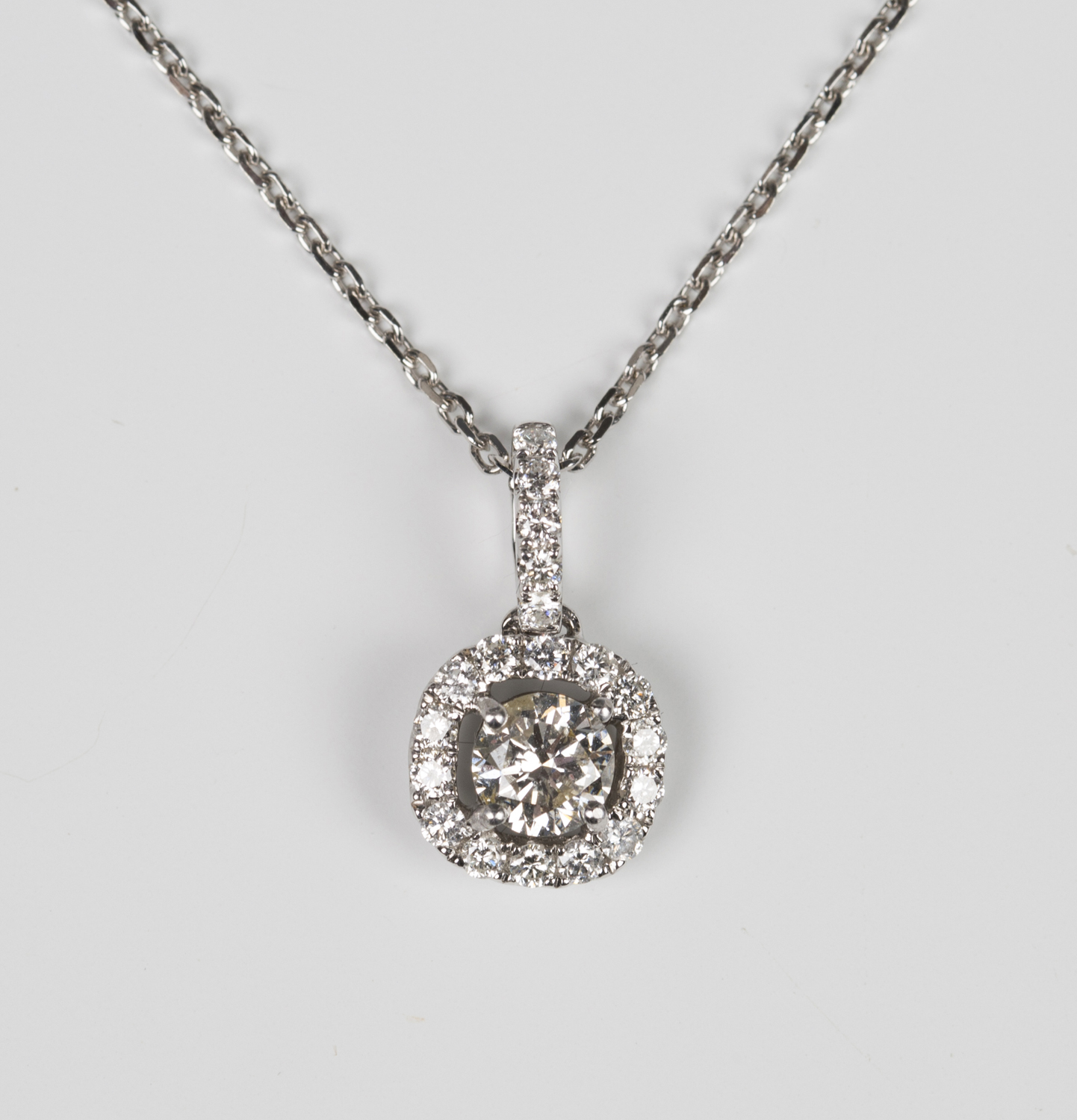 A white gold and diamond pendant, claw set with the principal circular ...