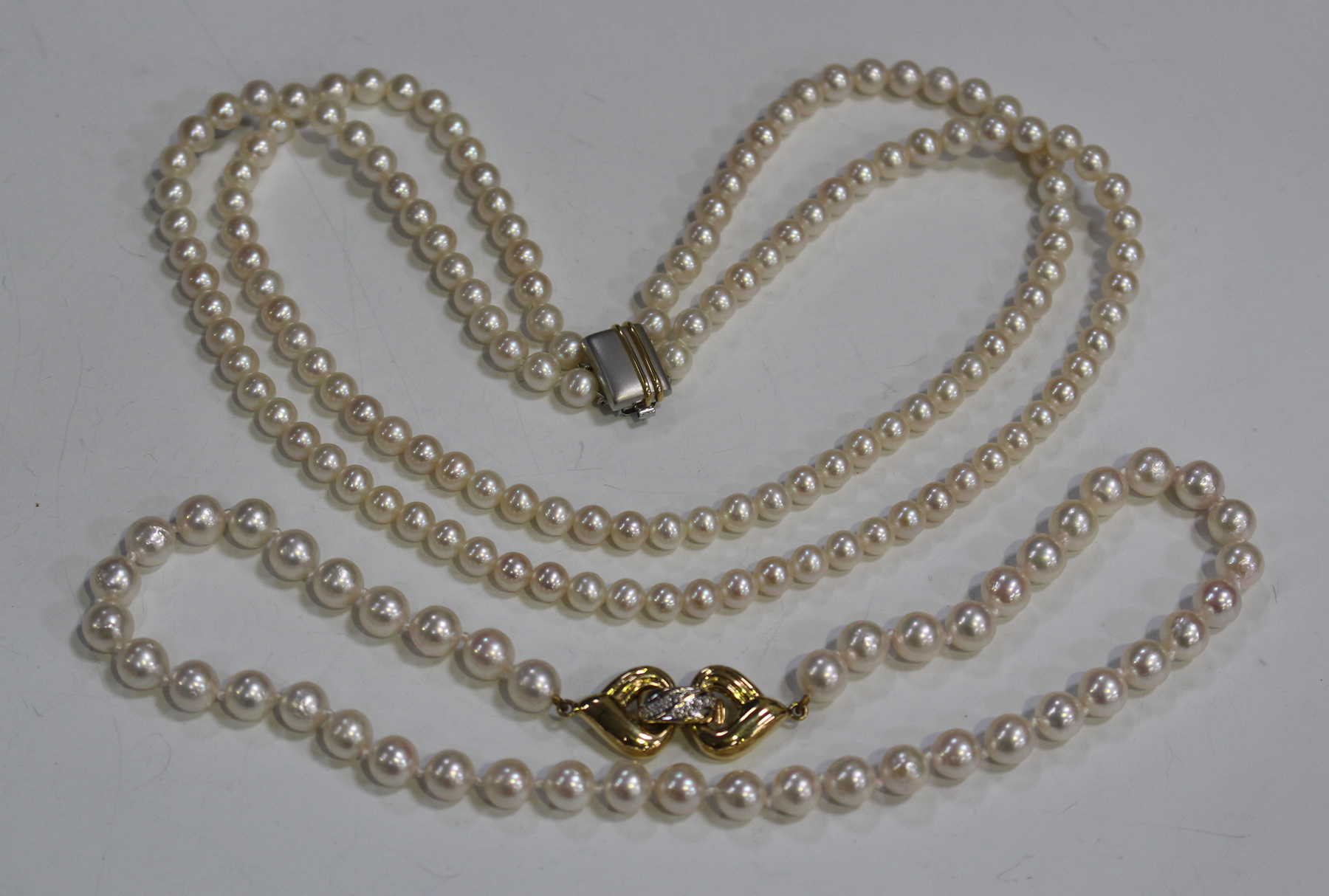 A two row necklace of uniform cultured pearls on a platinum and gold ...
