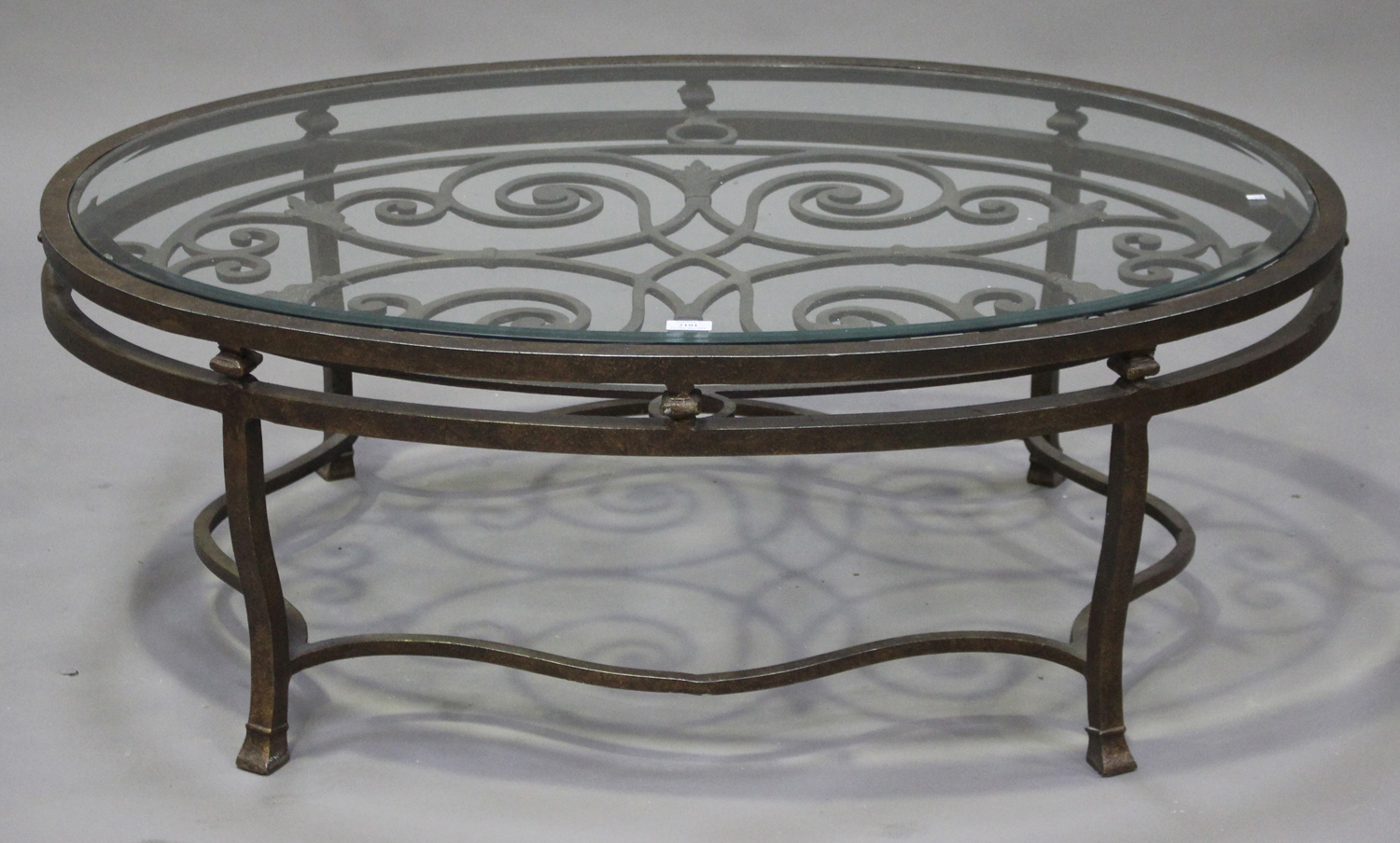 A modern bronzed aluminium and glass oval coffee table with scrolling ...