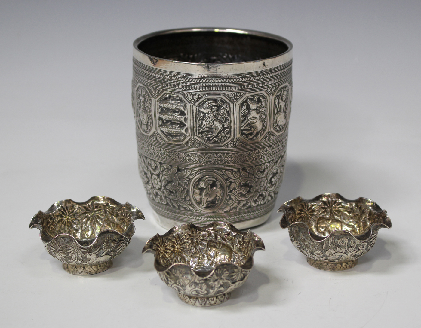 An Indian white metal beaker, decorated in relief with figures and ...