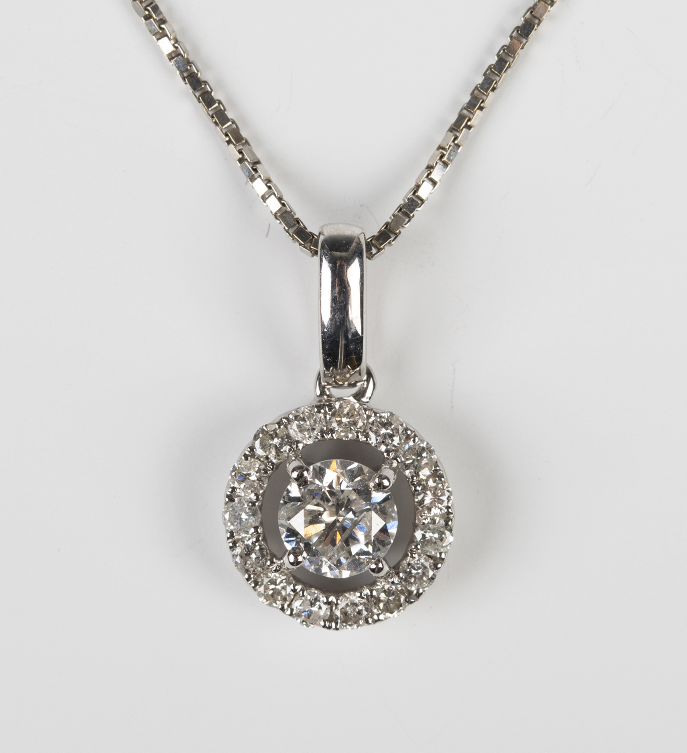 A white gold and diamond pendant, claw set with the principal circular ...