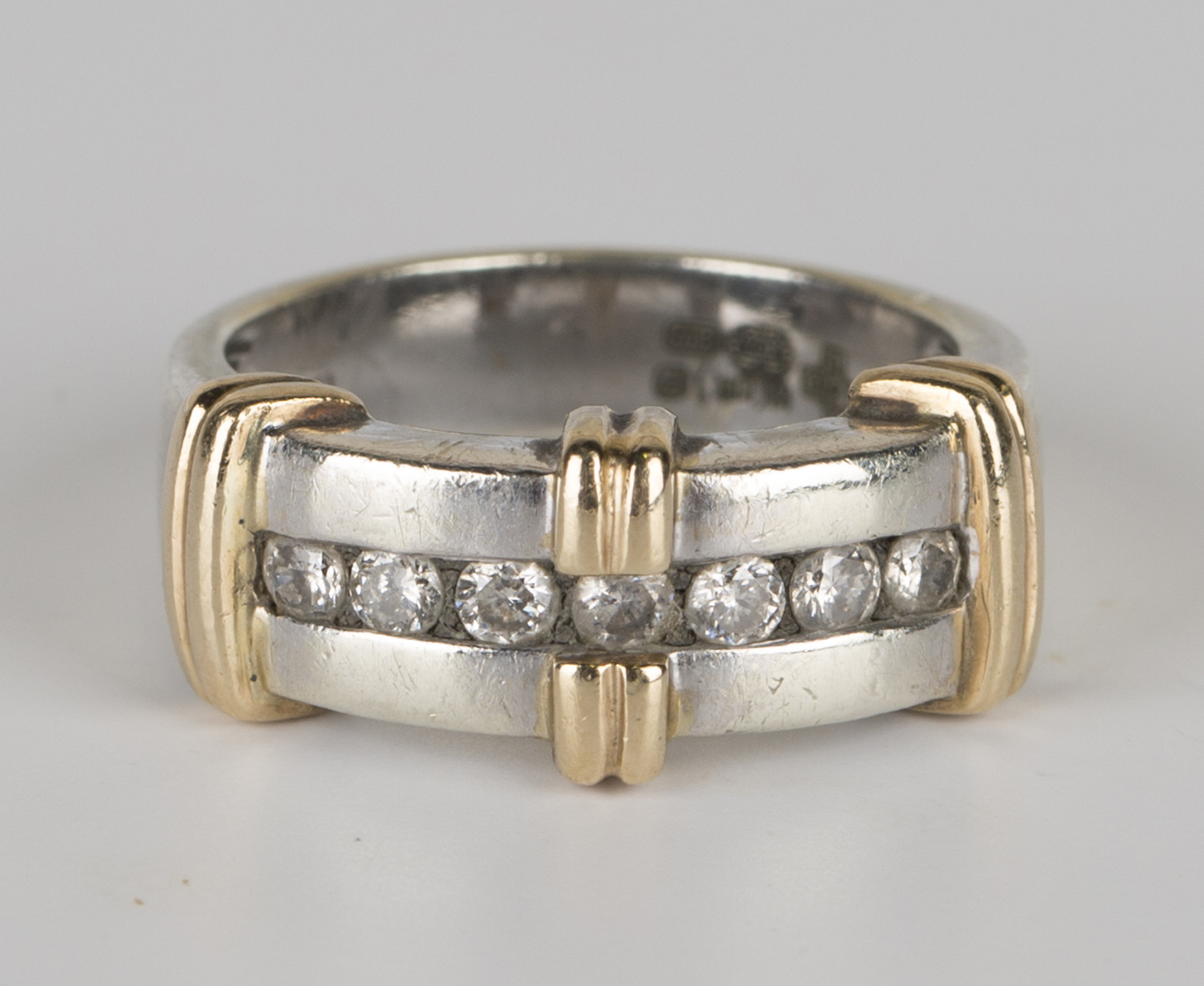A 9ct yellow and white gold ring, mounted with a row of seven circular ...