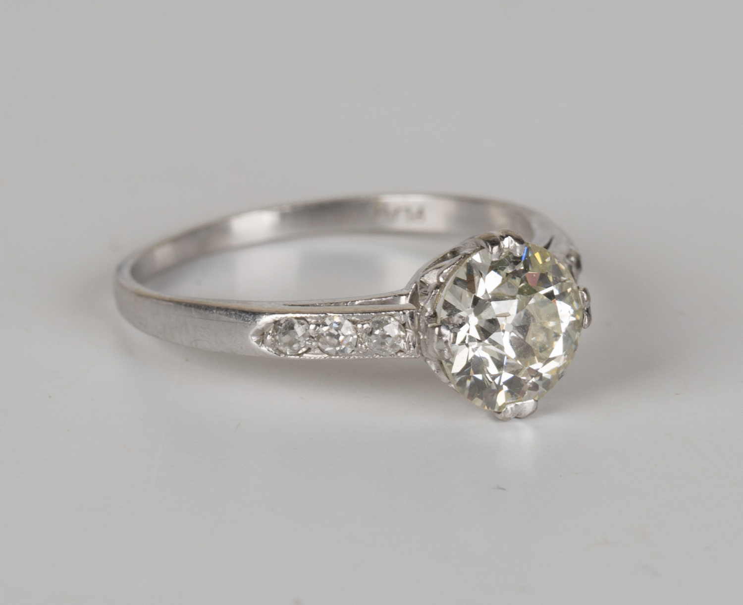 A platinum and diamond ring, claw set with a cushion shaped diamond ...