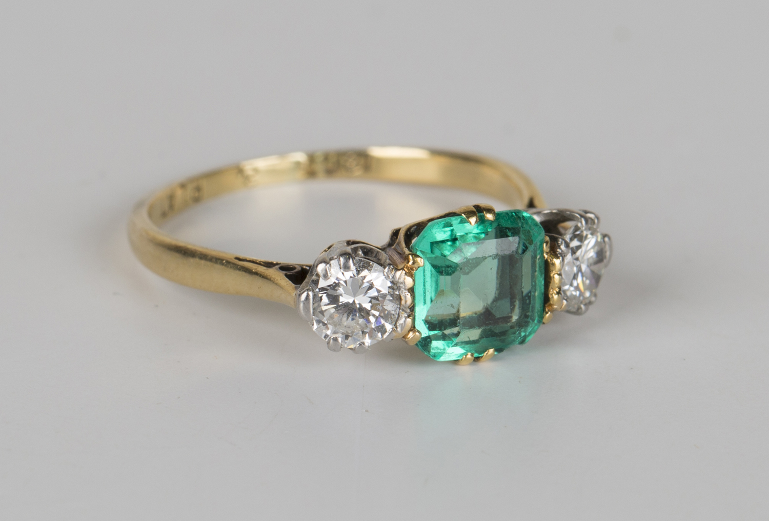 A gold, platinum, emerald and diamond three stone ring, claw set with ...