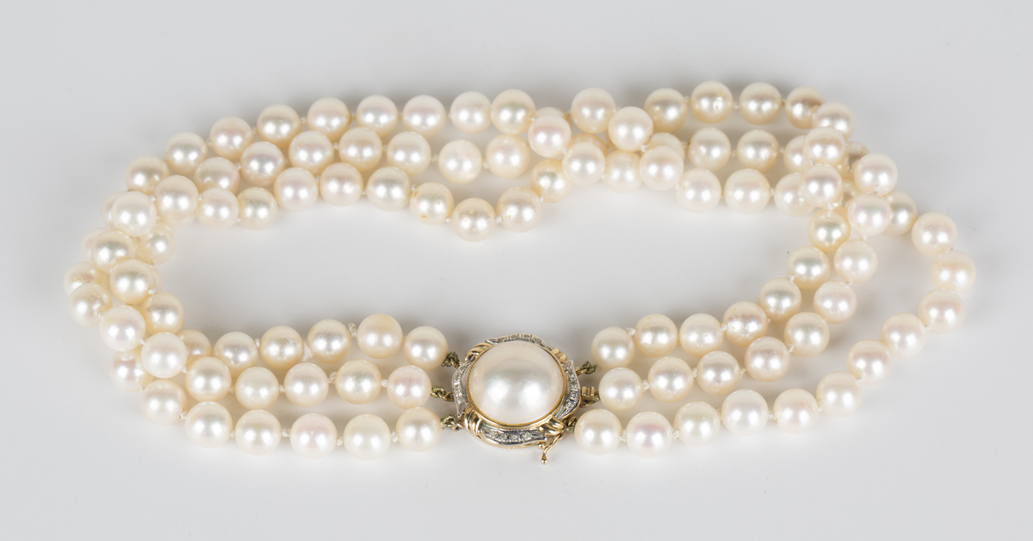 A three row necklace of cultured pearls on a mabé pearl set gold clasp ...