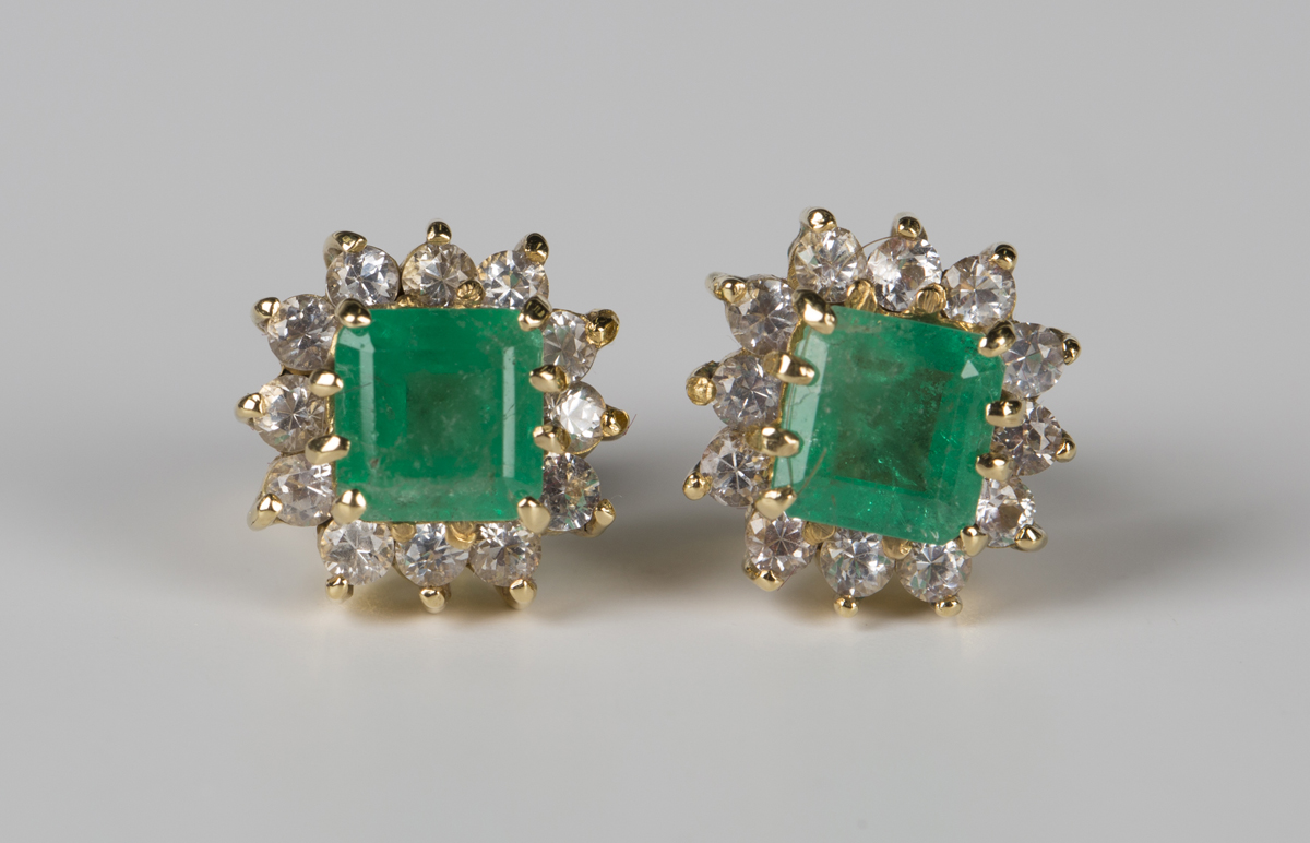 A pair of emerald and colourless gem set cluster earstuds, each claw ...