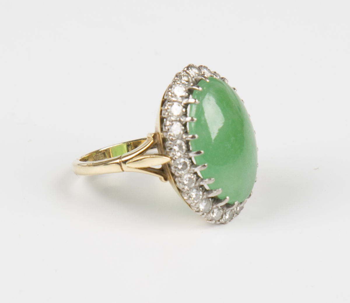 A gold, jade and diamond oval cluster ring, claw set with the oval jade ...