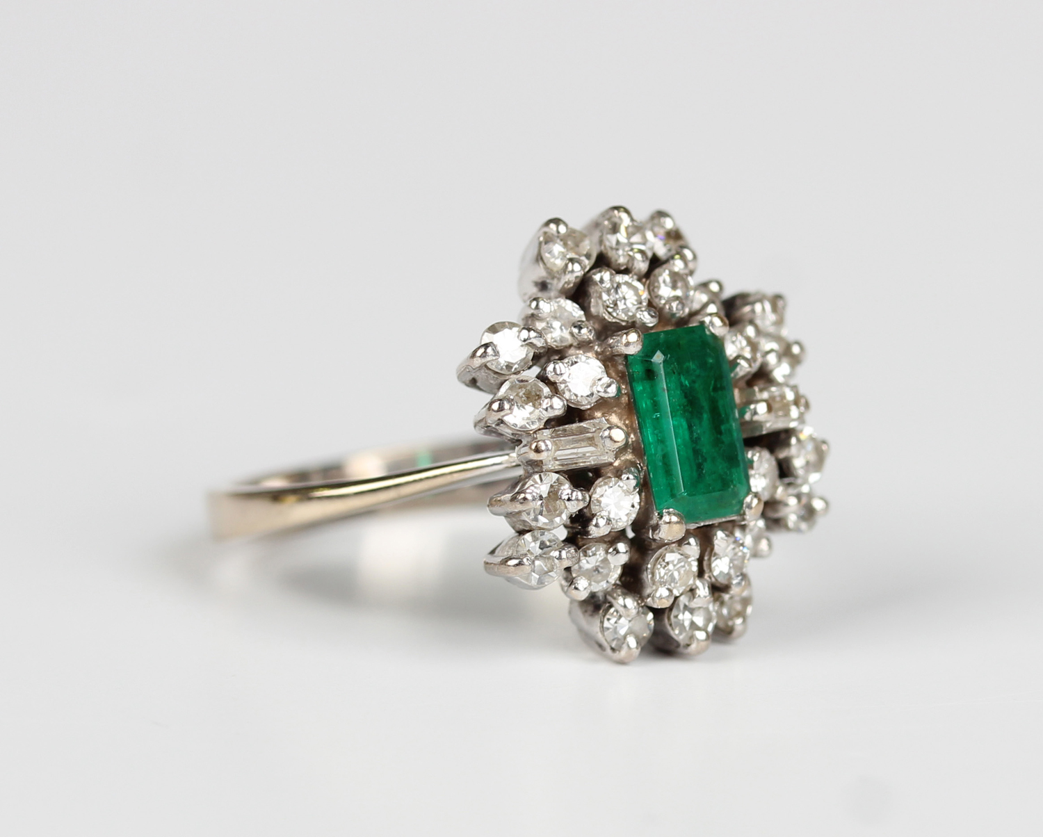 A white gold, emerald and diamond cluster ring, claw set with a ...